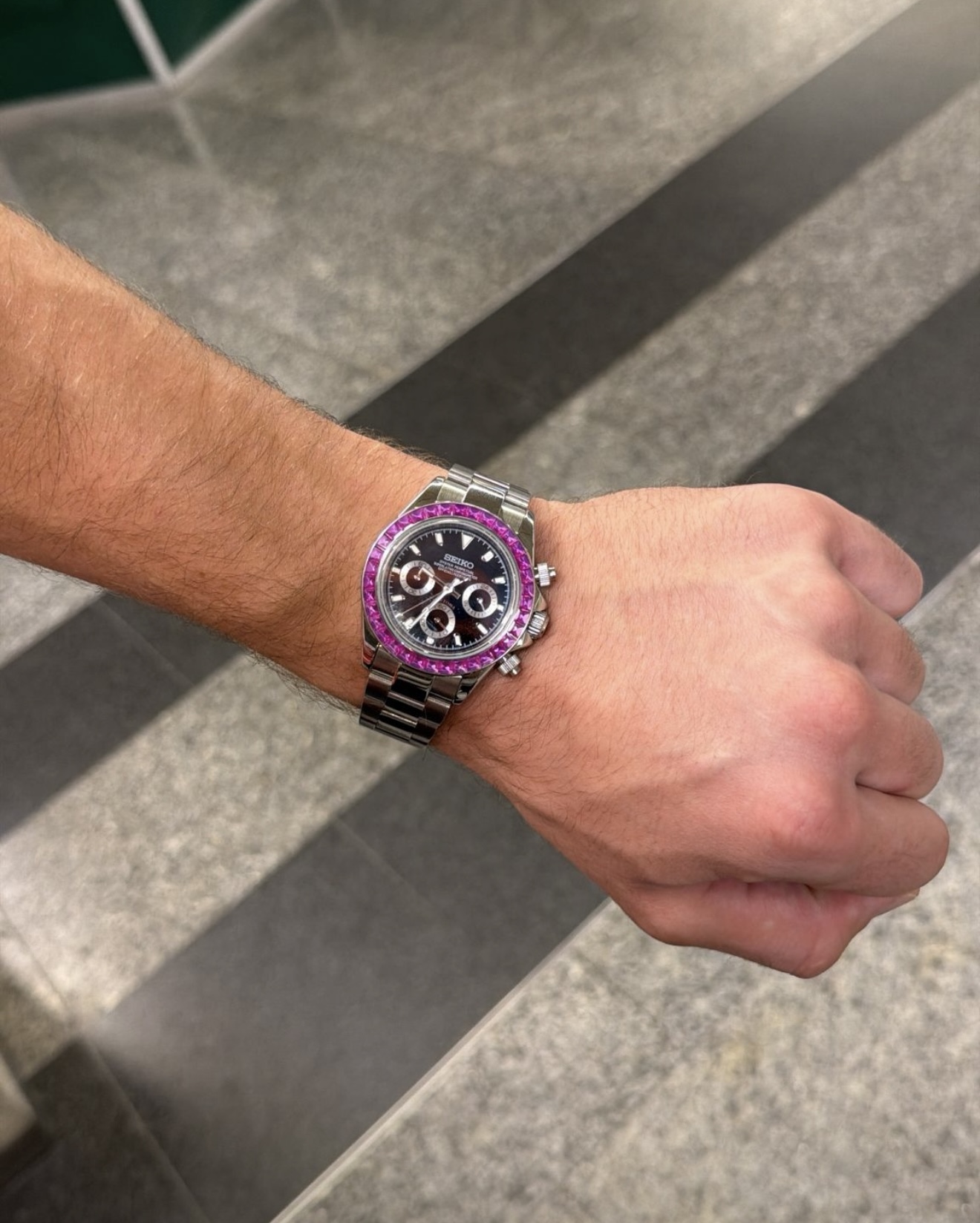 Client portant un chronographe acier à lunette sertie rose