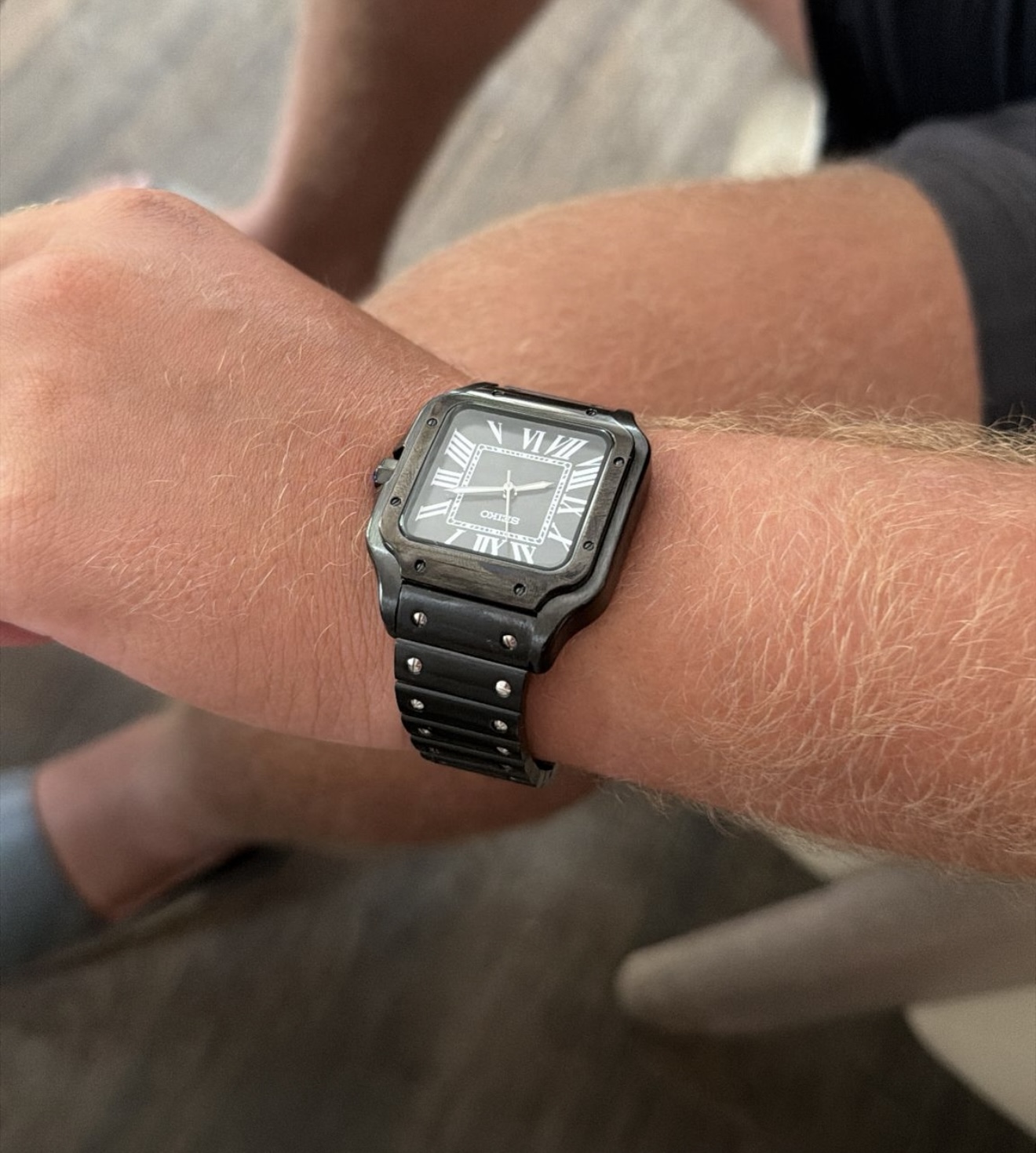 Client portant une montre carrée noire chiffres romains