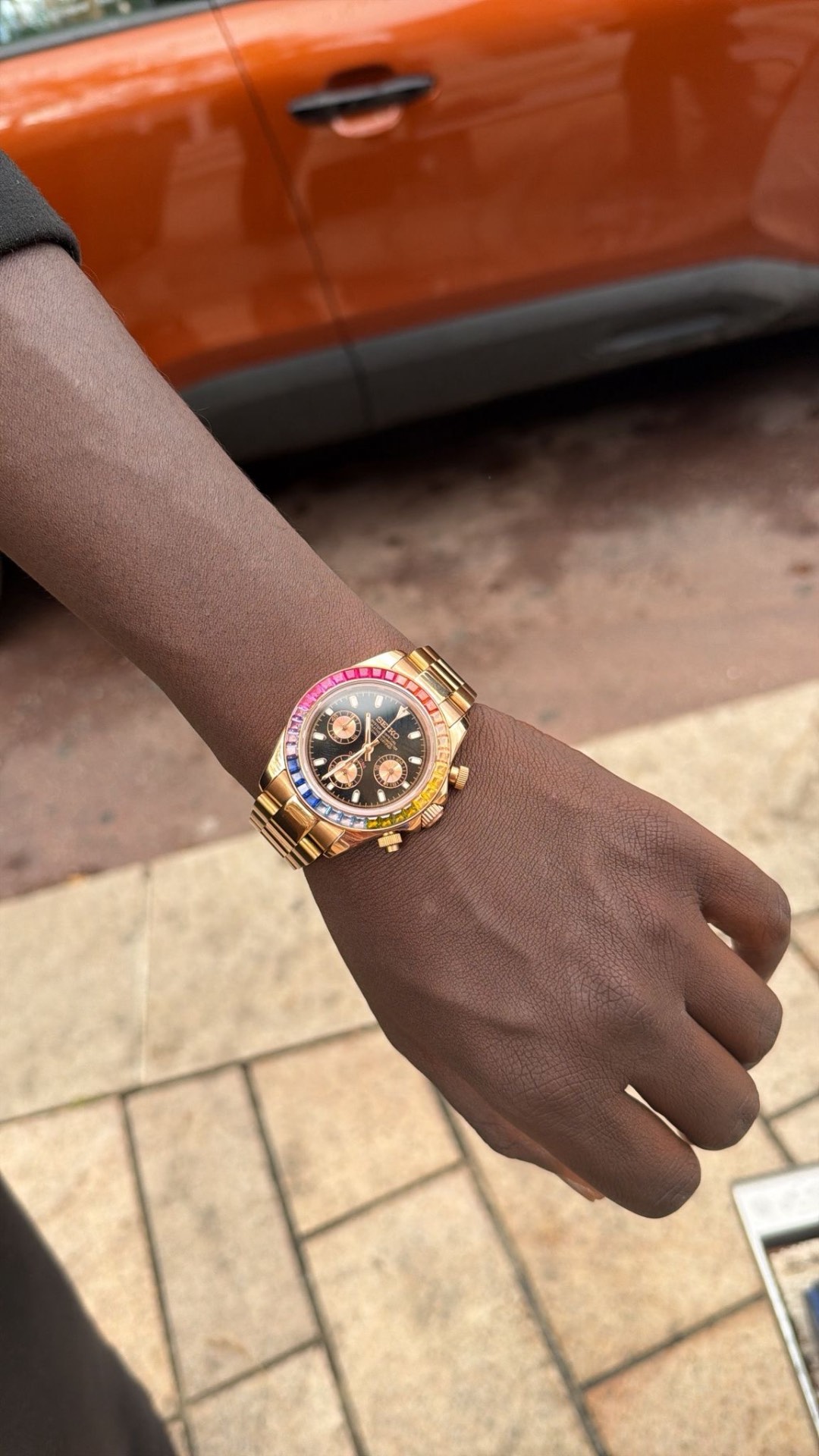 Client portant une montre dorée à lunette multicolore